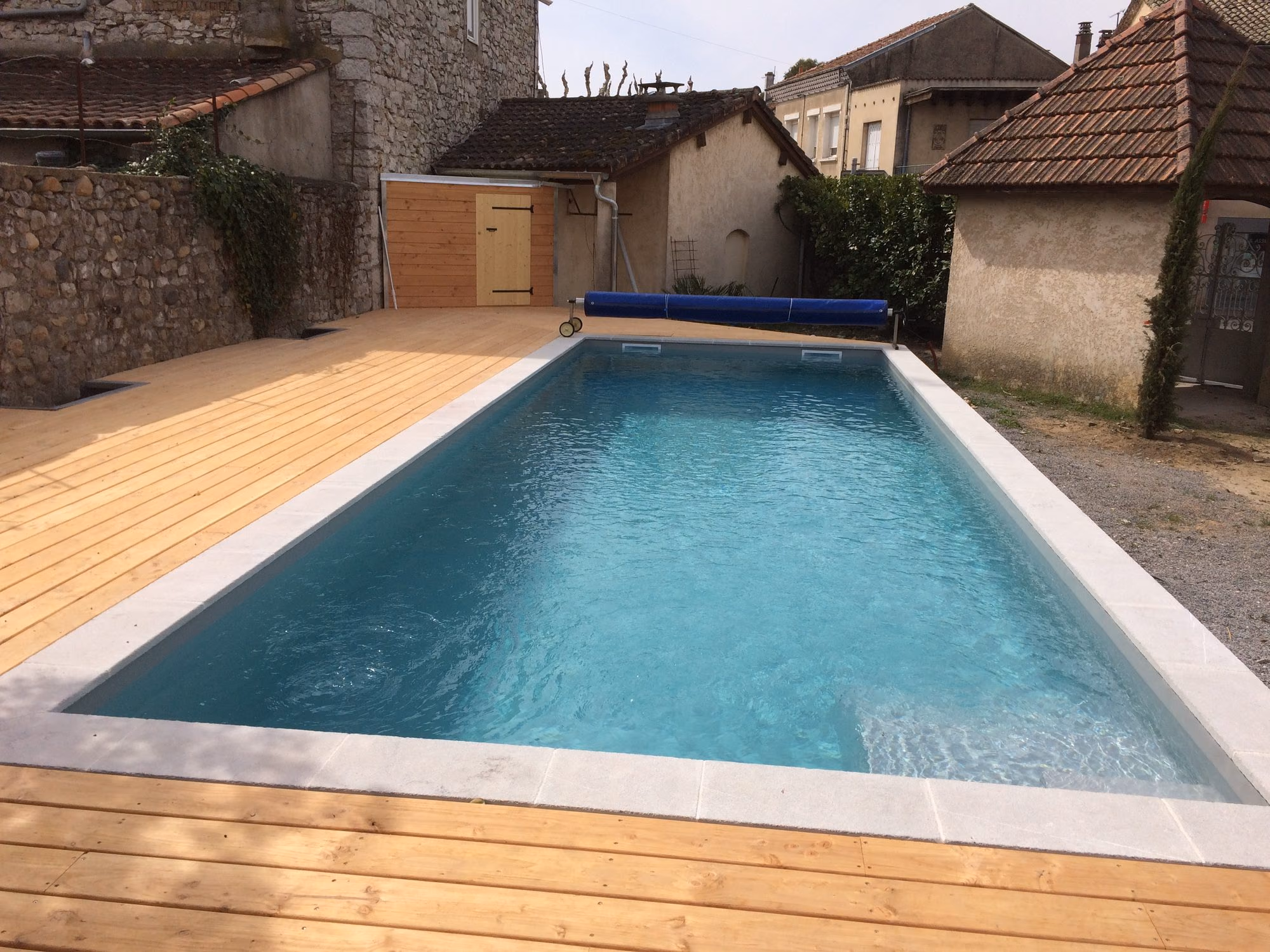 Piscine turquoise dans une cour de village en pierre à Ruoms