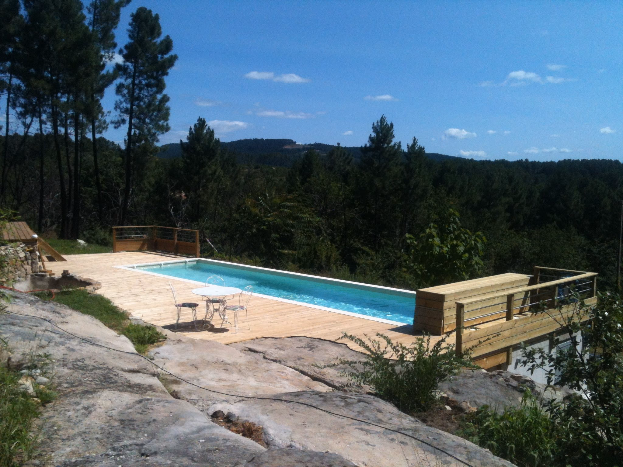 Couloir de nage et terrasse en bois posés sur un rocher, face à la forêt, en sud Ardèche