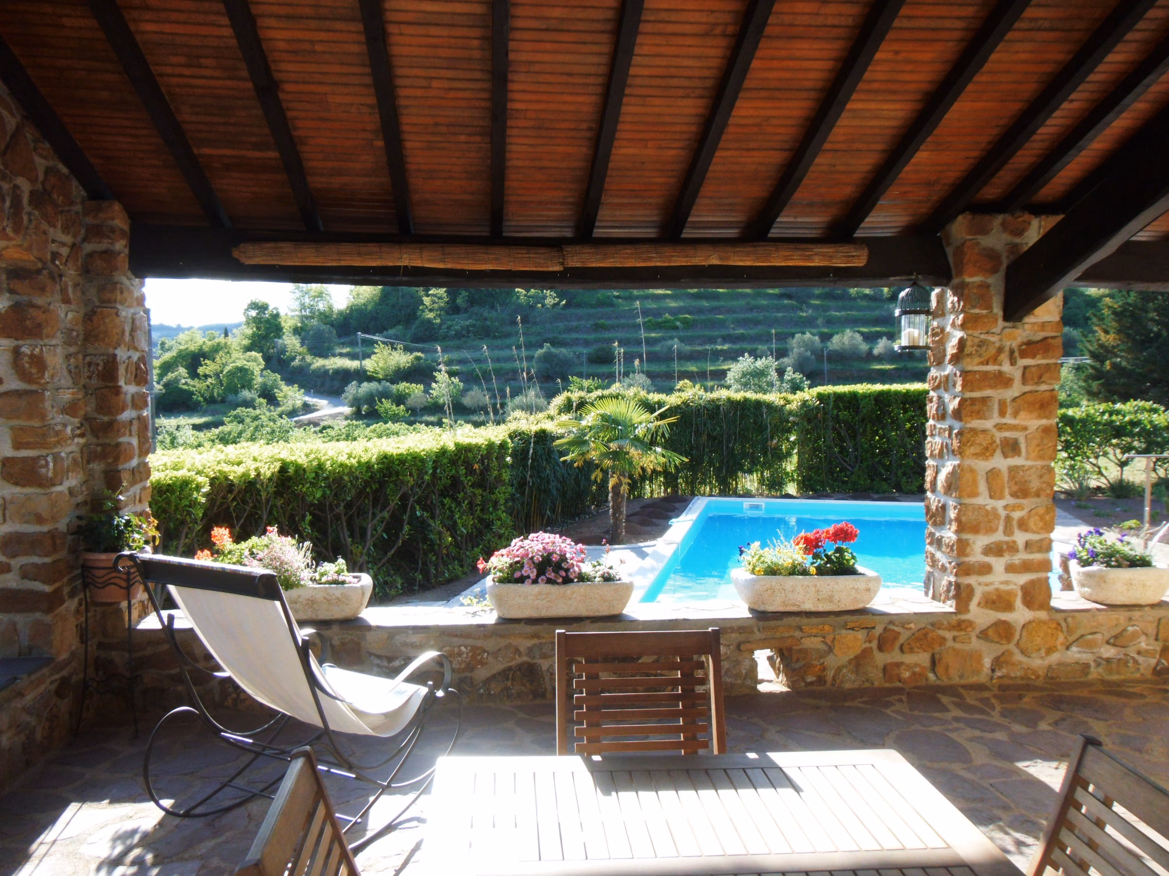 Piscine livrée vue depuis une terrasse couverte en pierre, coteaux en terrasses
