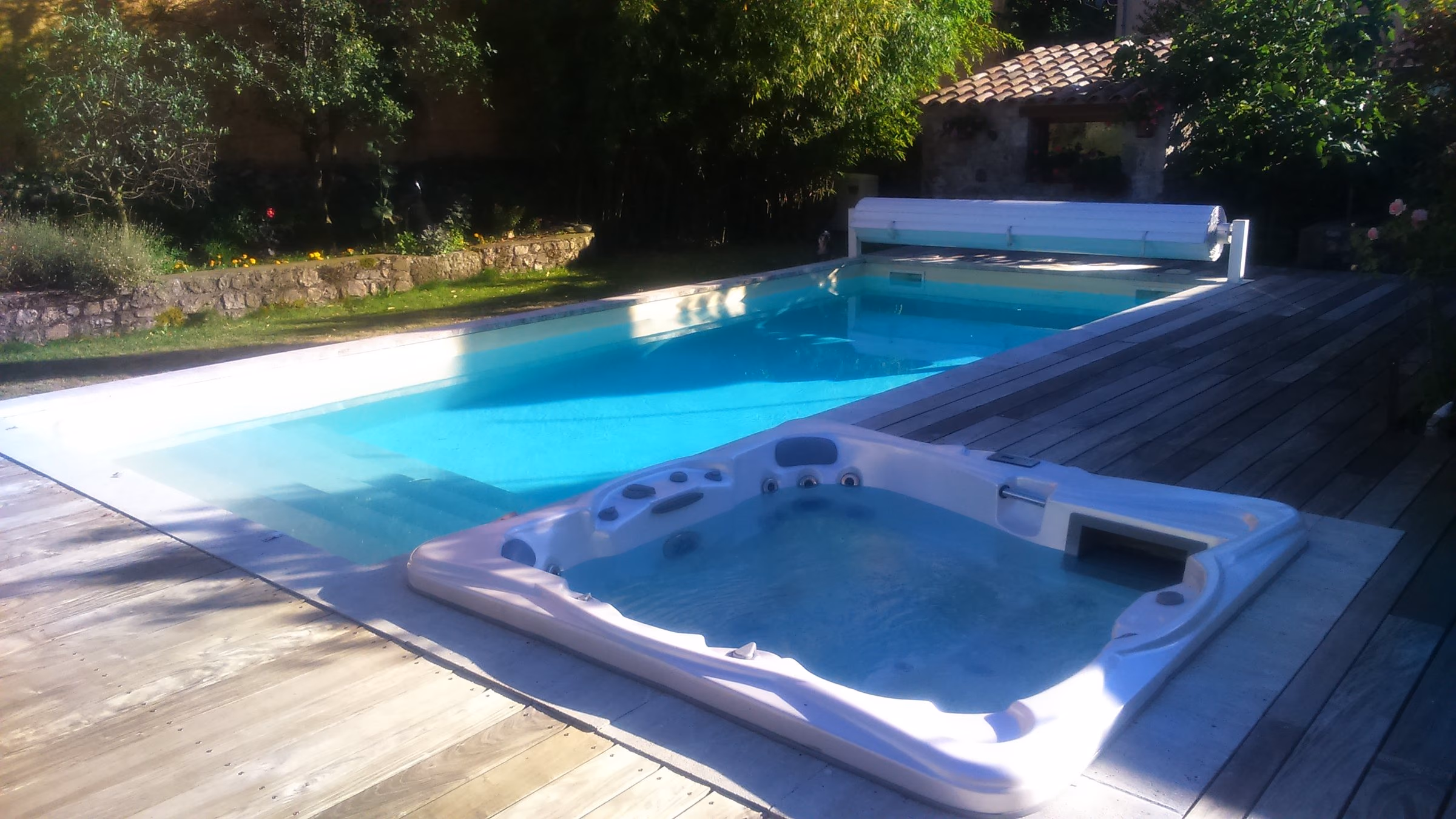 Spa encastré dans la terrasse en bois, au bord de la piscine